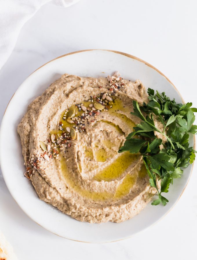 roasted eggplant dip in a plate garnished with parsley and seeds